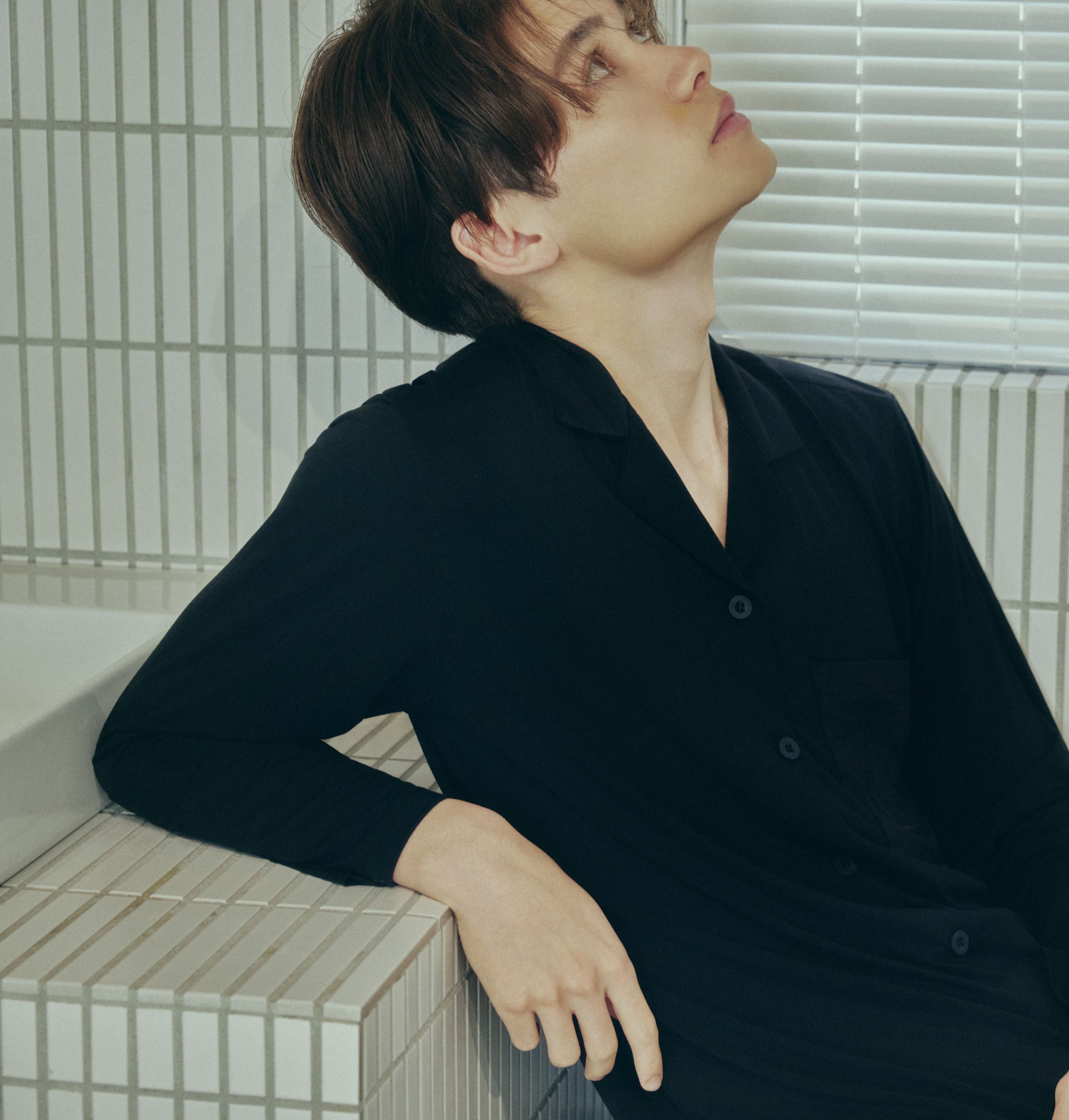 黒いAMBIENTパジャマを着て髪をまとめる女性